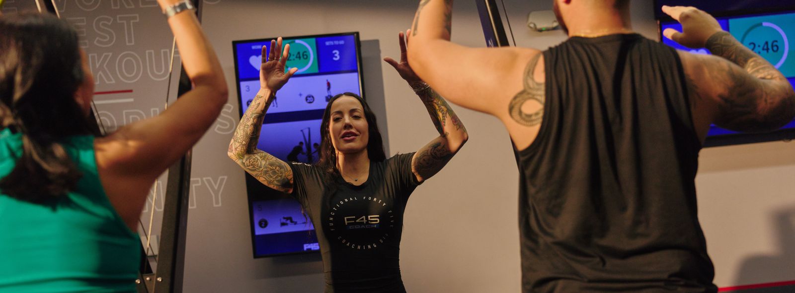 A coach leading members, arms raised, at an F45 studio