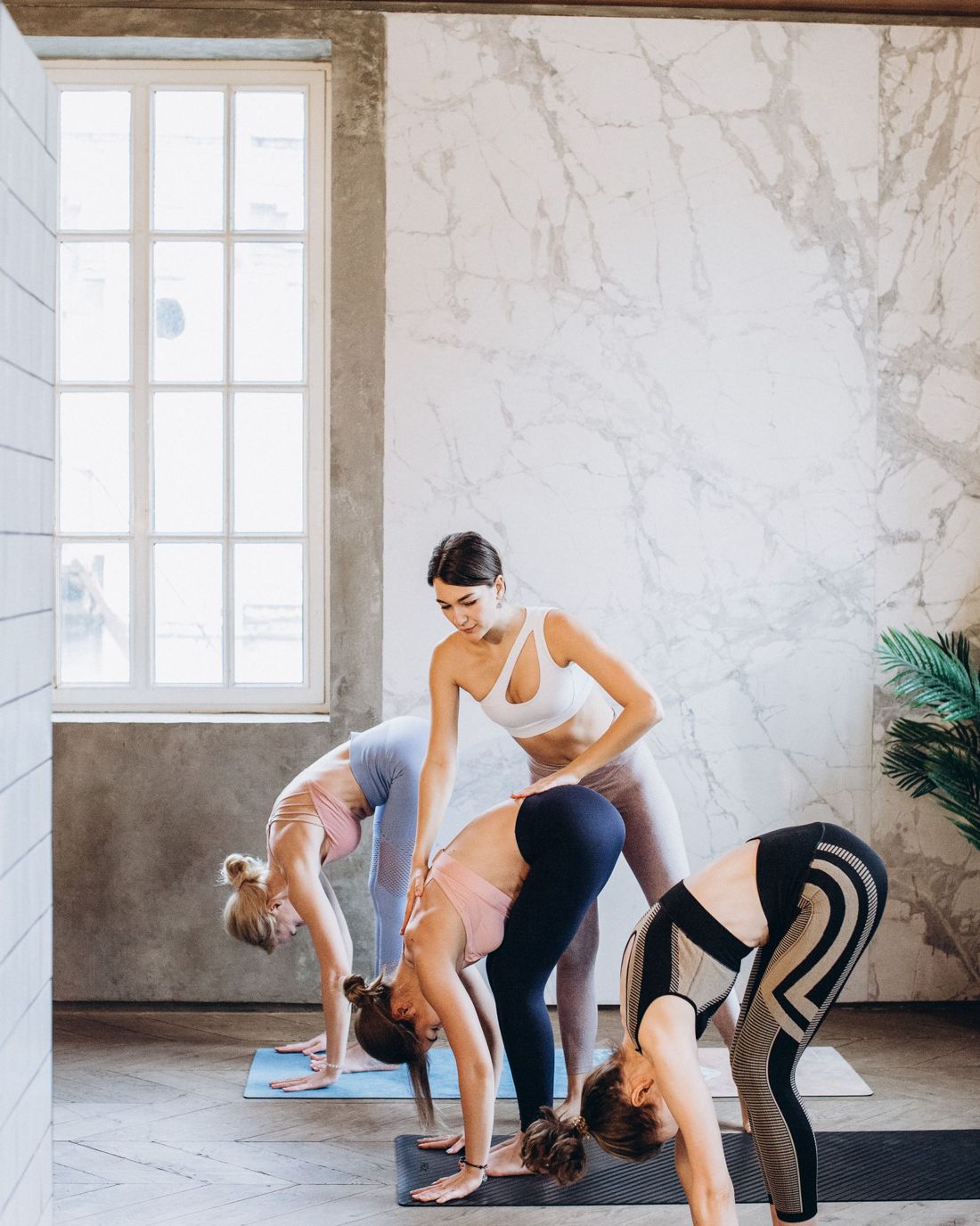 A yoga instructor adjusting students mid-class in a bright studio